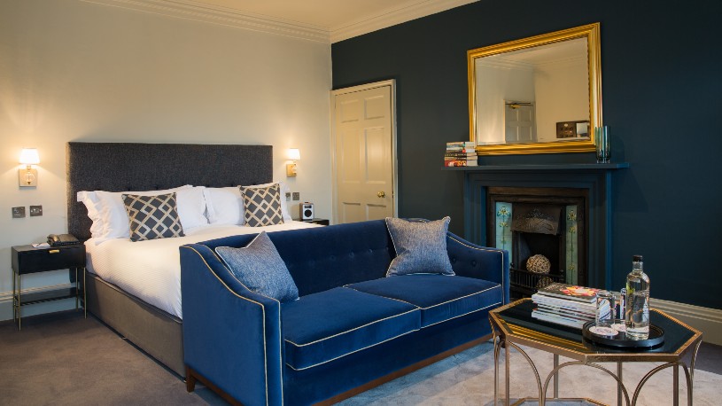 Double bedroom with blue sofa at end of bed at The Queenberry Hotel